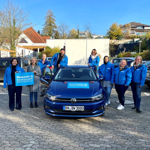 Mitarbeiter der Diakonie stehen neben dem neuen Auto.