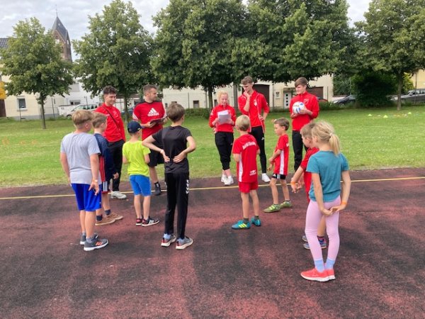 Kinder und Leiter von Sport im Park stehen zusammen und besprehcen sich, bevor es losgeht.