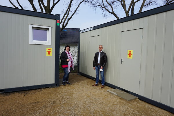 V.l. Angela Peters und Udo Müllenborn vom Gebäudemanagement der Gemeinde Swisttal vor den Sanitärcontainern.