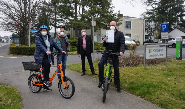 Auf dem Bild sind die Mitarbeiter der Verwaltung zu sehen, die die neuen elektrischen Fahrräder präsentieren. Martin Koenen hat seine Ernennungsurkunde zum Mobilitätsmanager in der Hand.