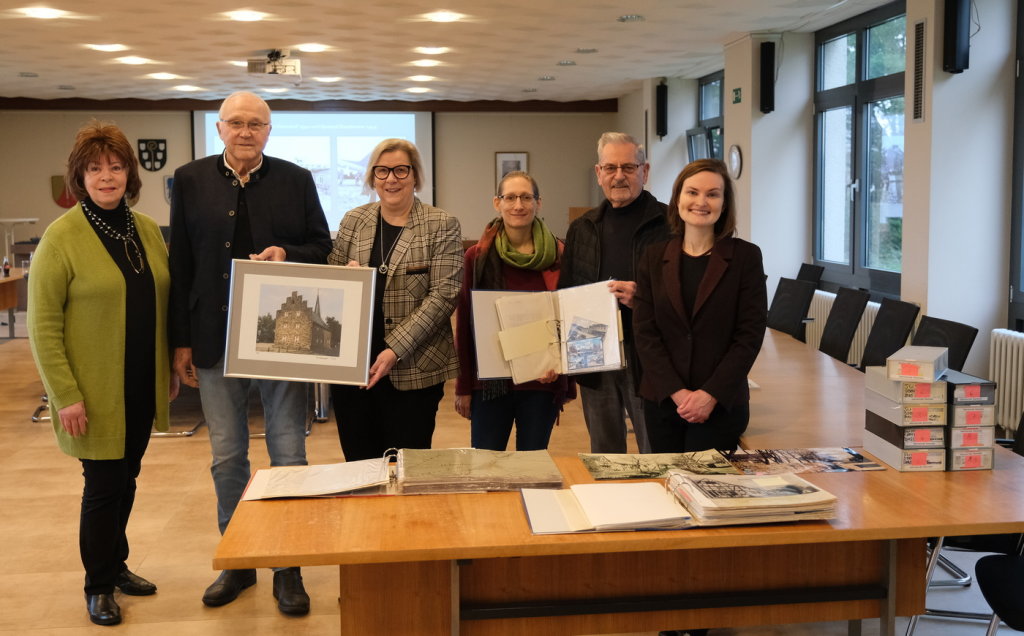 Auf dem Bild sind sechs Personen zu sehen. Die Mitglieder des Vereins Zehnthaus e.V. übergeben den Mitarbeiterinnen des Gemeindearchivs historisches Bildmaterial aus dem Vereinsarchiv. Auf dem Foto sind Anna Louise Wiener -2. Vorsitzende Verein Zehnthaus e.V.-, Bernhard Hiesinger -Vorsitzender Verein Zehnthaus e.V.-, Bürgermeisterin Kalkbrenner, Jeannine Kunz -Gemeindearchiv-, Klaus Peter Scholz -Kulturwart Verein Zehnthaus e.V.- und Hanna Albers -Gemeindearchiv-.