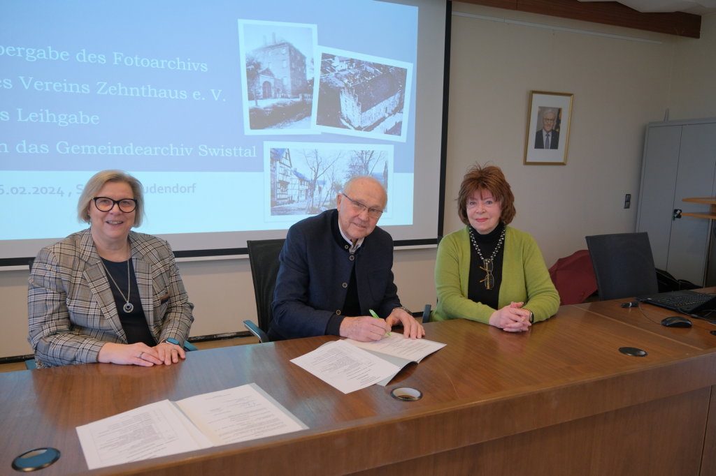 Bürgermeisterin Kalkbrenner, Bernhard Hiesinger -Vorsitzender des Vereins Zehnthaus e.V.- und Anna Louise Wiener -2. Vorsitzende des Vereins Zehnthaus e.V.- unterzeichnen den Depositalvertrag auf der Empore im Ratssaal.