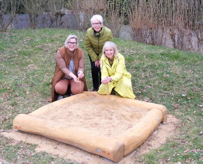 Der neue Sandkasten auf dem Spielplatz „Am Wehrbusch“ Das Foto zeigt den Sandkasten mit Bürgermeisteirn Kalkbrenner und zwei Ehrenamtlerinnen der Fair-Kauf-Kleiderstube Buschhoven