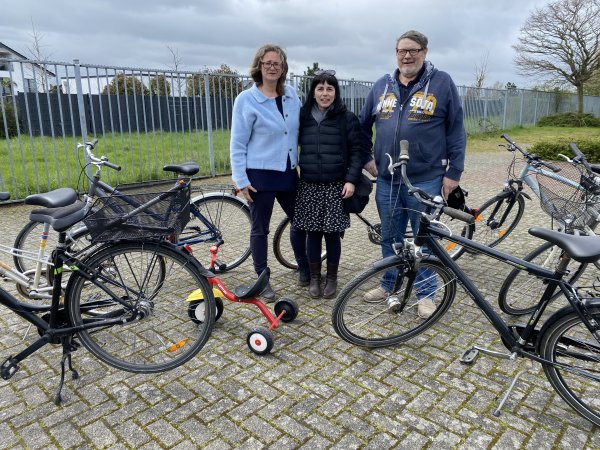 Dr. Barbara Gunst-Assimenios, Sozialarbeiterin Alexia Xiromeriti und Reiner Lanzrath bei der Fahrradübergabe