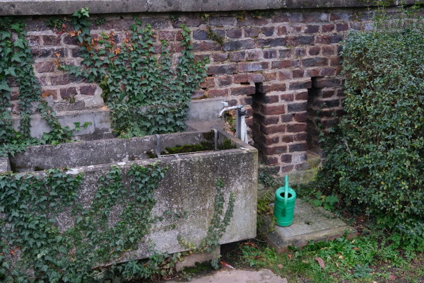 Auf dem Bild ist ein Wasserhahn auf einem Friedhof zu sehen.